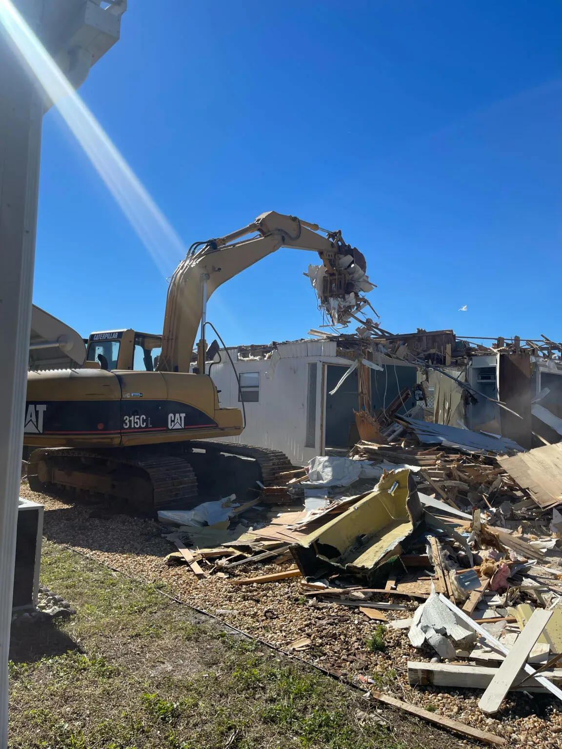 CAT excavator demolishing a structure under a blue Florida sky